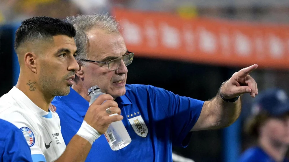 Marcelo Bielsa pointing while standing on the sidelines with Luis Suarez